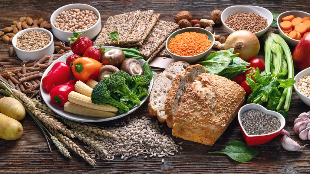 tavola piena di alimenti ricchi di fibre come verdure, legumi e cereali