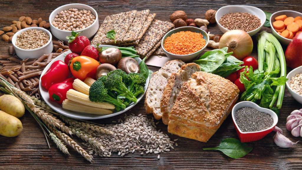 tavola piena di alimenti come verdure, pane, semi, legumi