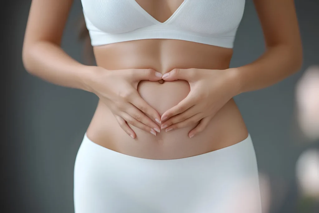 Giovane donna vestita in intimo bianco che disegna un cuore con le dita davanti alla sua pancia