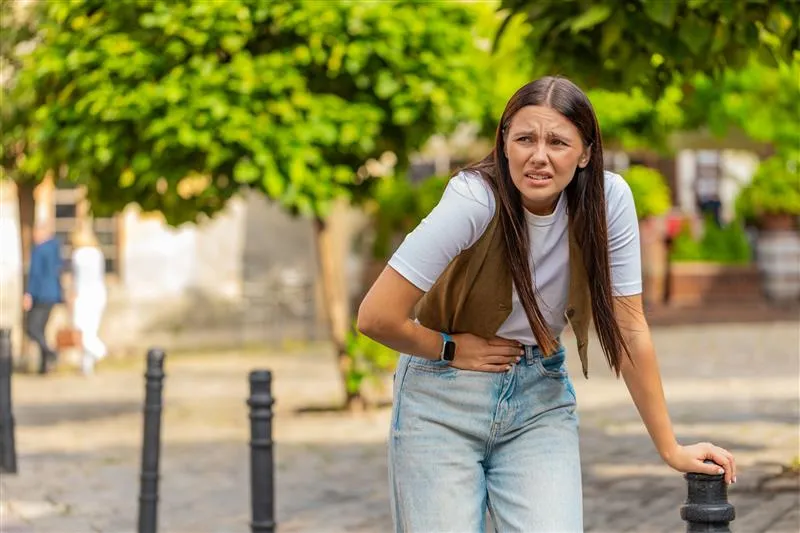 Giovane ragazza per strada che avverte un improvviso mal di pancia