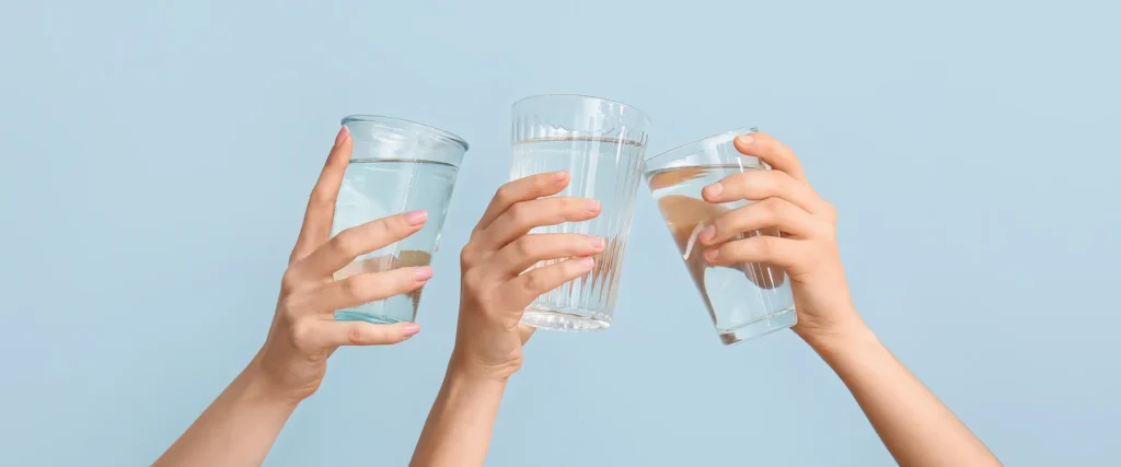 Tre mani sollevano bicchieri d'acqua