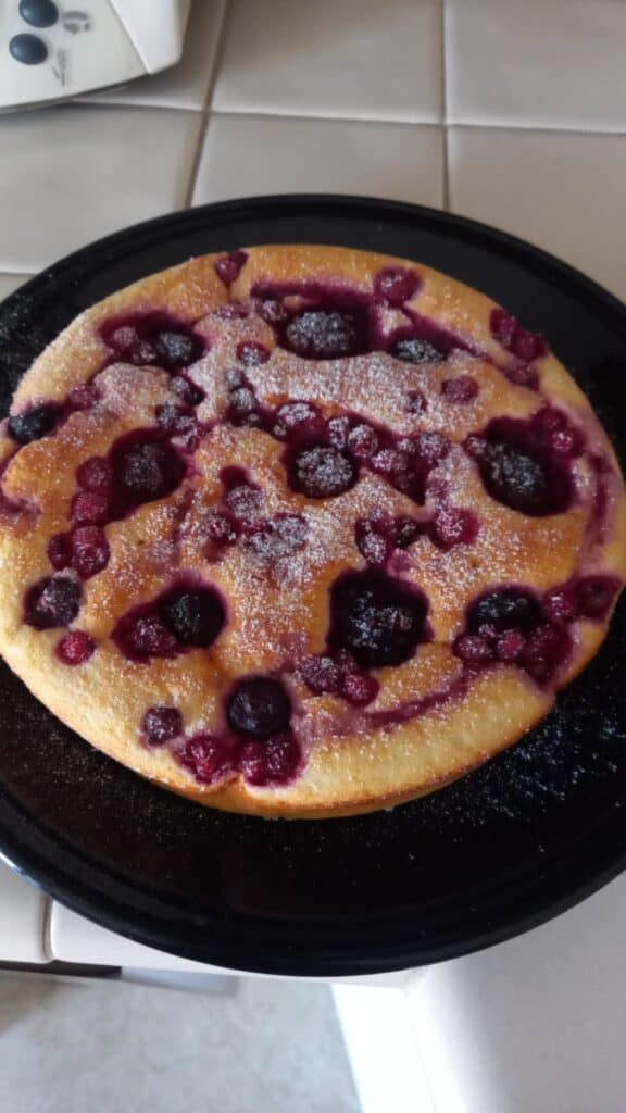 Torta di frutti di bosco e zucchero a velo su piatto nero.
